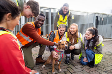 volunteers gather around a dog for a picture outside